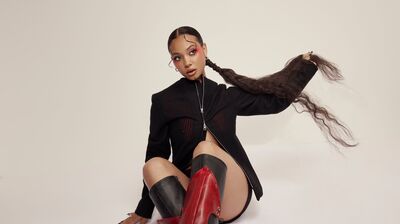 Someone with red knee high boots sat on the floor holding their long ponytail