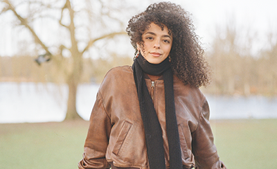 Dalia Al-Dujaili stands in a park against a fence in the wind.