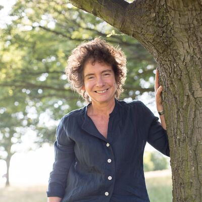 Jeanette Winterson standing by a tree.