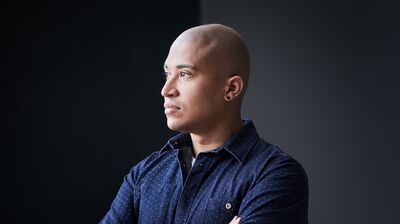 Man in blue shirt with arms folded looking out to the left