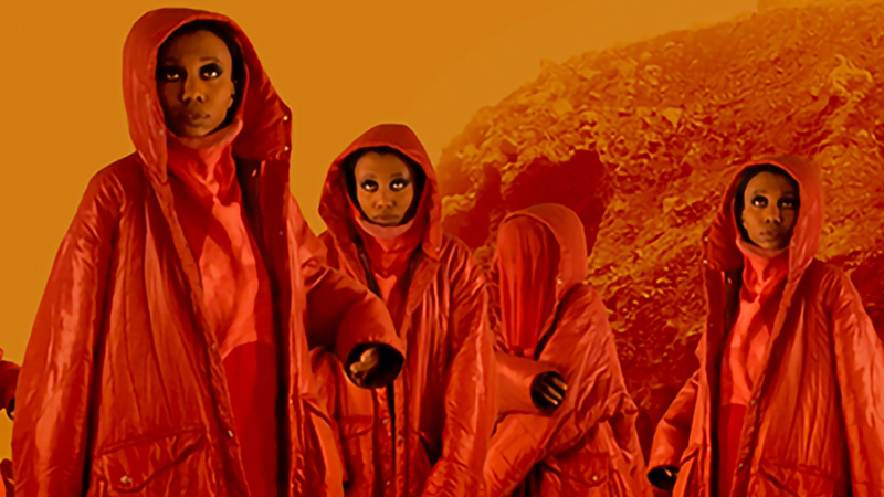 Multiple images of same person in red jacket and hood looking up on a background that looks like the surface of the sun