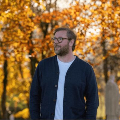 Damian Barr surrounded by autumn trees.