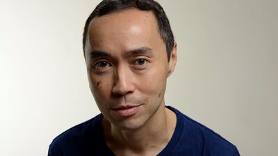 Portrait of a person with short dark hair, wearing a blue t-shirt and has brown eyes