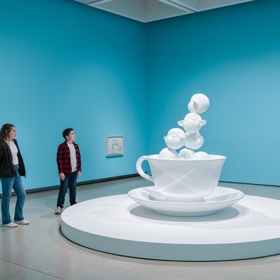 A little child with ginger hair is peeking through an installation in Replay.