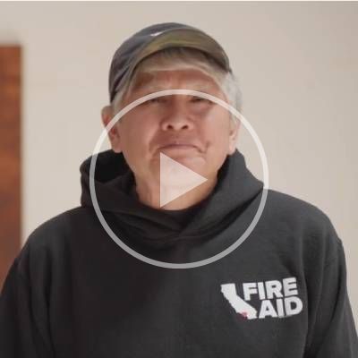 Yoshitomo Nara smiling at the camera with a play button overlaid on