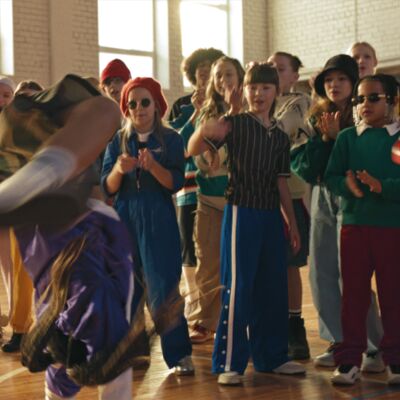 Group of children watching someone dance and move on their hands