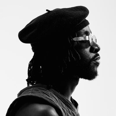 Black and white portrait of a persons side profile, they are wearing a hat, sunglasses and a tank top