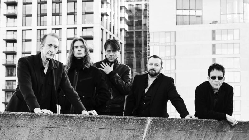 A band standing on a concrete balcony with buildings in the background