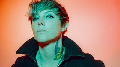 A woman looking directly at the camera with head slightly tilted up expressing a confident and tough vibe.