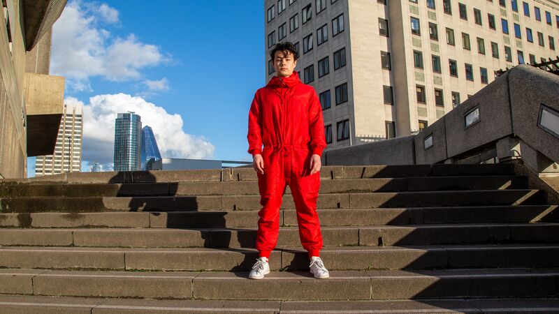 Sean Shibe, all dressed in red, stands on the stairs to the Hayward Gallery