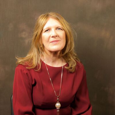 Woman in a red top wearing a long necklace with a spherical pendant.
