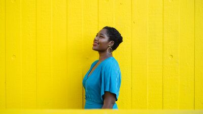 Nardus Williams wearing a bright blue dress in front of a yellow wall