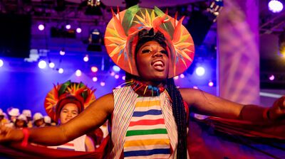 A woman wearing a colourful head piece dancing