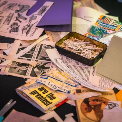 A table covered in pieces of paper and scissors as a part of a collage workshop
