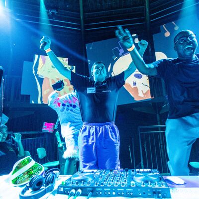 Two young men throw their hands in the while DJ'ing