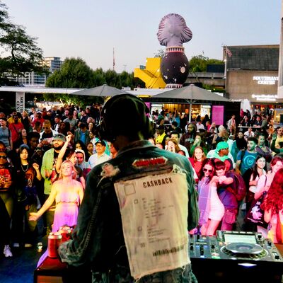 A man dj'ing in front of crowd on the Riverside Terrace