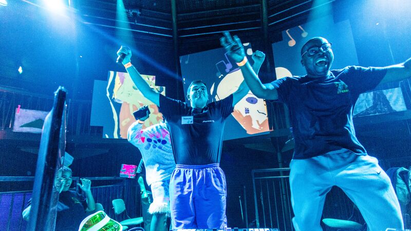 Two young men throw their hands in the while DJ'ing