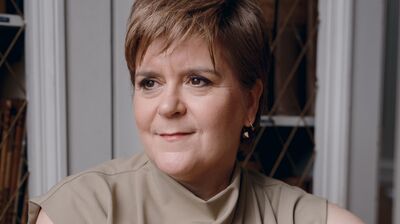 Nicola Sturgeon wearing a beige top leaning on the back of a chair.