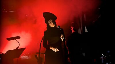 A woman dressed in black wearing a pointed hat holding a mic