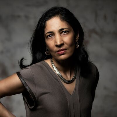 Kiran Desai wearing a grey top and necklace against a grey background.
