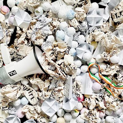 Megaphone lying on scrunched up balls of paper and other origami shapes