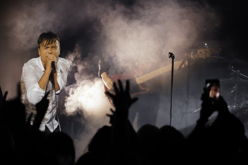 Suede seen from far away, the hands of an enthusiastic fan in the air in the foreground