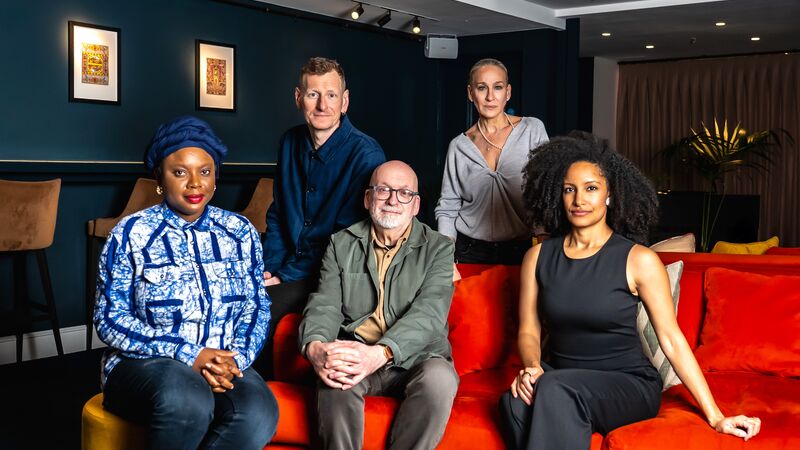 Booker Prize 2025 Judges gathered together by a red sofa.