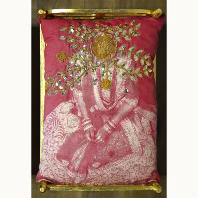 Red coushion with traditional embroidery of a woman sitting and yellow beaded flowers where her face would be