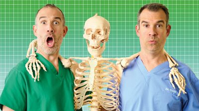 A skeleton hangs between the shoulders of two doctors who are looking shocked
