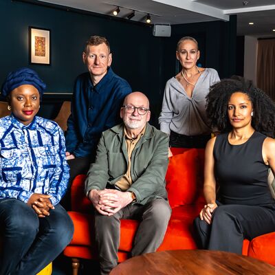 Booker Prize 2025 Judges gathered together by a red sofa.