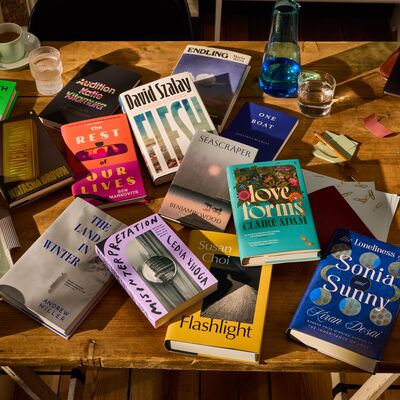 Wooden table with books longlisted for the Booker Prize 2025 and pots of tea, biscuits and a laptop