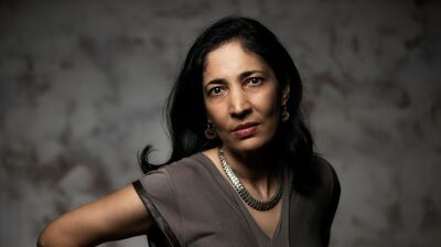 Kiran Desai wearing a grey top and necklace against a grey background.