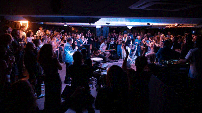 A string quartet holding their violins, wearing neutral clothing