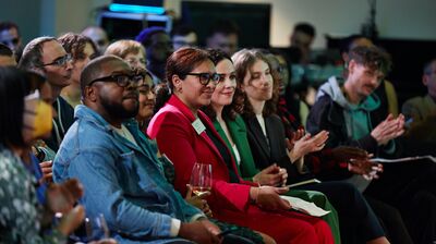 Audience members watching an event whilst looking to the right with smiles.