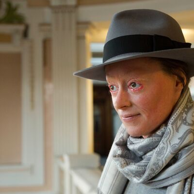 Rachael Boast wearing a grey hat and scarf whilst facing and looking left off camera.