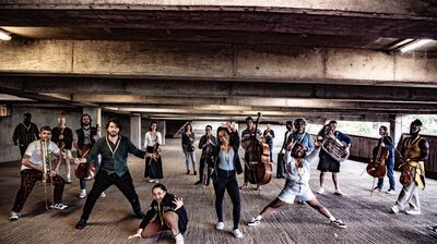 The Multi-Story Orchestra make some large poses in a concrete carpark