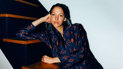 On wooden steps, a woman in a blue dress rests her head against her hand