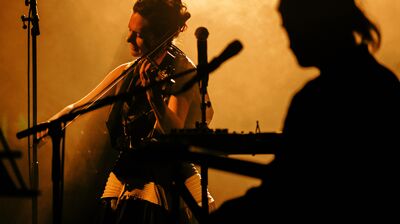 Violinist Rakhi Singh playing violin in a dark fog among silhouettes of people