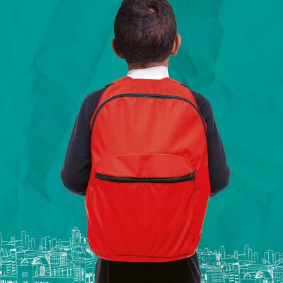 A boy is standing his back to the viewer. He is wearing a red backpack and has dark, short hair.