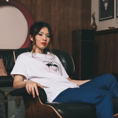 Someone wearing a white t-shirt and blue trousers, sitting in a leather chair in a lounge with wood panelling