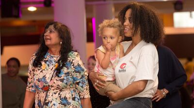 Two women, one holding a baby, enjoy a dance event.