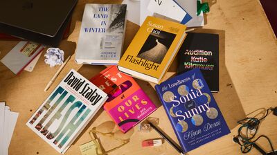 Six different books displayed on a wooden table