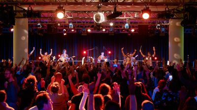Afla Sackey + Afrik Bawantu performing to a large dancing audience in a room with a shiny disco ball