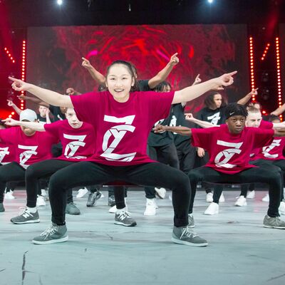 ZooNation dancers on stage, wearing red tops and pointing their fingers