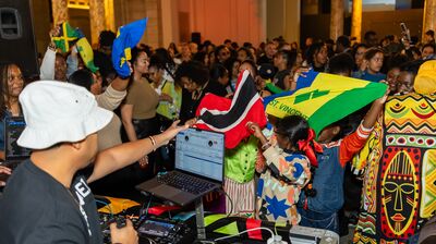 DJ using decks and laptop faces the crowd waving flags
