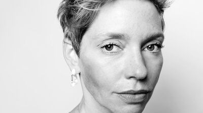 Black and white close-up portrait of a woman with short pixie hair and a neutral expression, wearing a single modern hoop earring.