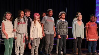 A group of children singing enthusiastically on a stage