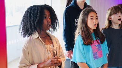 Four young people stood together all singing and looking to the right