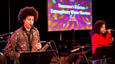 A group of children singing enthusiastically on a stage