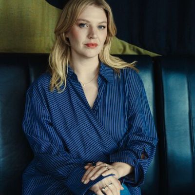 Singer Self Esteem, a young woman with long blond hair, sits on a leather sofa seat